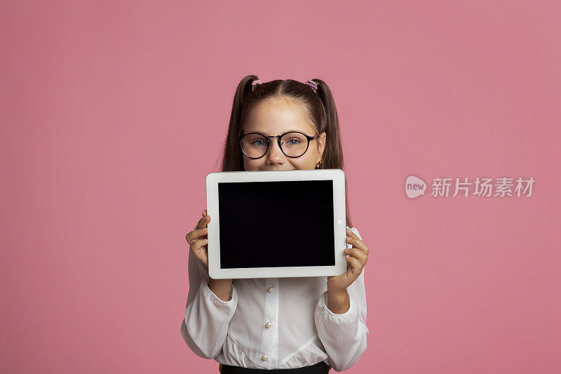 儿童教育和远程教育。戴眼镜的快乐女孩展示黑屏平板电脑