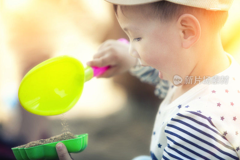 可爱的小男孩在热带海滩上玩海滩玩具