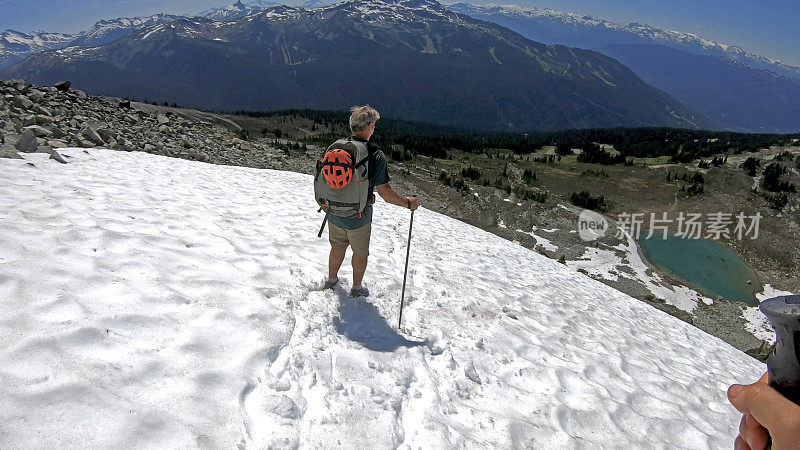 徒步旅行者沿着积雪的山坡跑下去