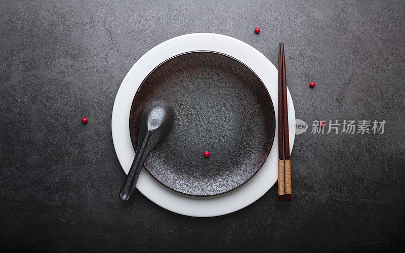 灰色的石头上放着空的陶瓷盘子、筷子和勺子