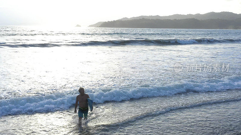 日出时分，一名男子带着冲浪板奔向太平洋