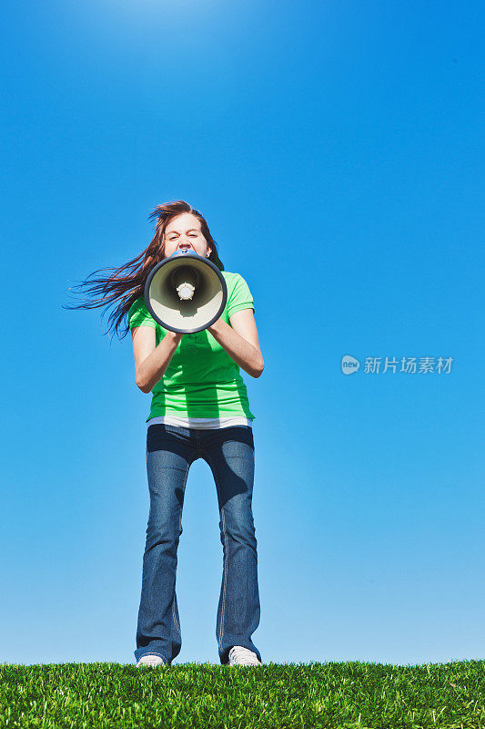 一个年轻女人对着扩音器大喊，对着晴朗的夏日蓝天