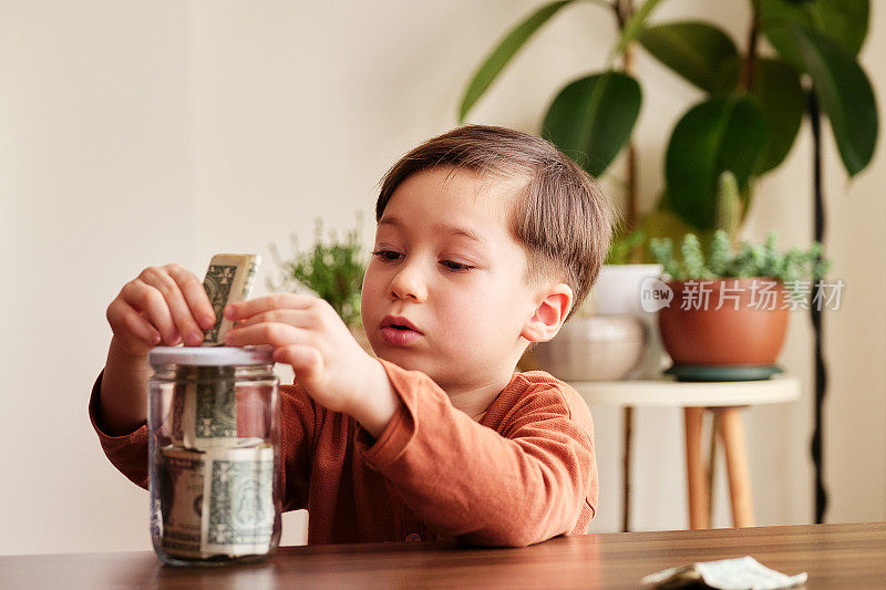 孩子在家里用玻璃罐子存钱