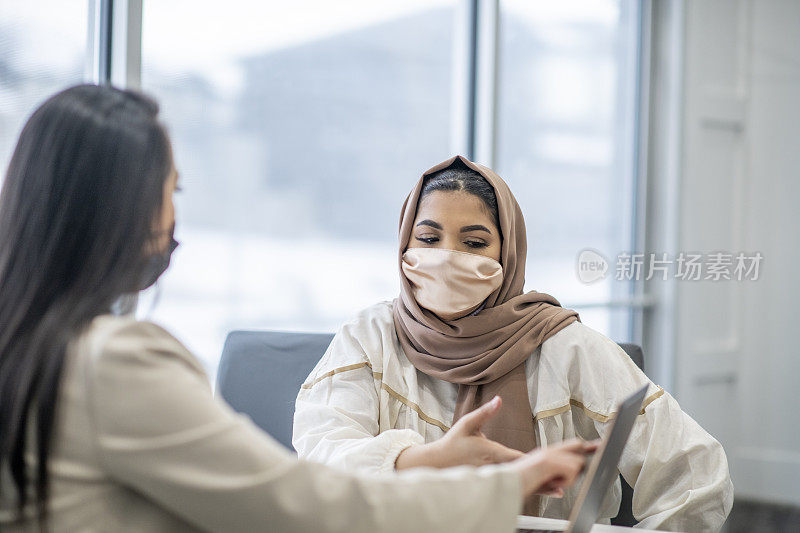 一名穆斯林妇女戴着头巾与一名财务规划师会面