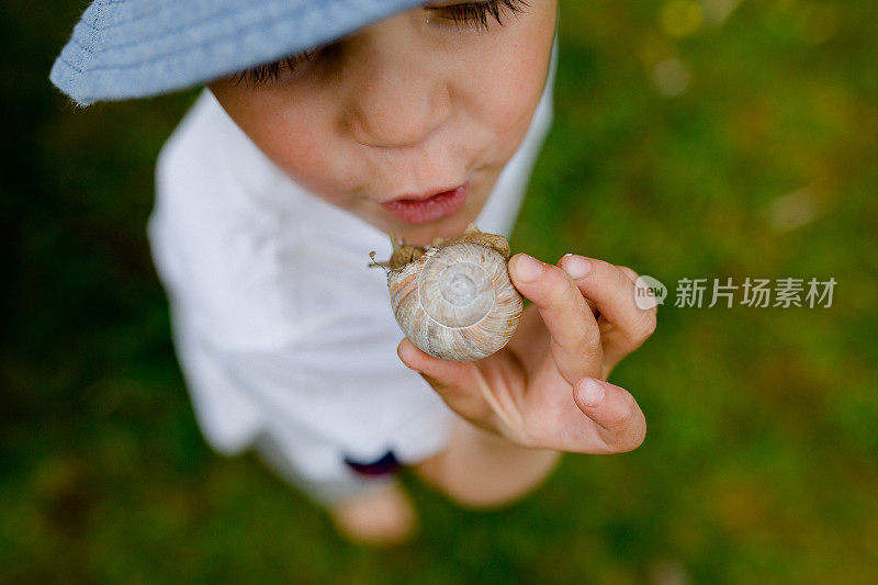 蹒跚学步的孩子手里拿着蜗牛