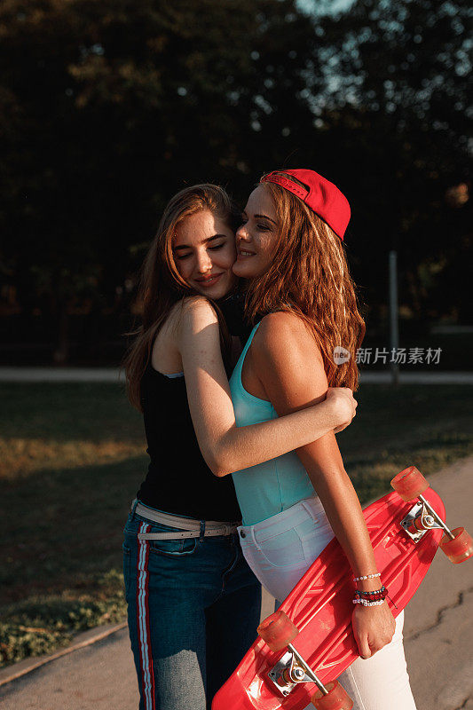 阳光灿烂的日子里，快乐的少女们在城市公园里拥抱