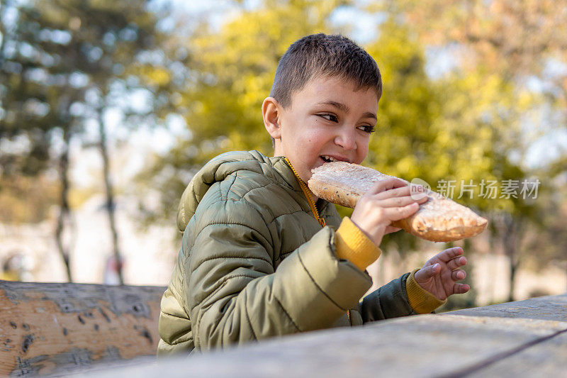 男孩在公园里吃着自制的面包