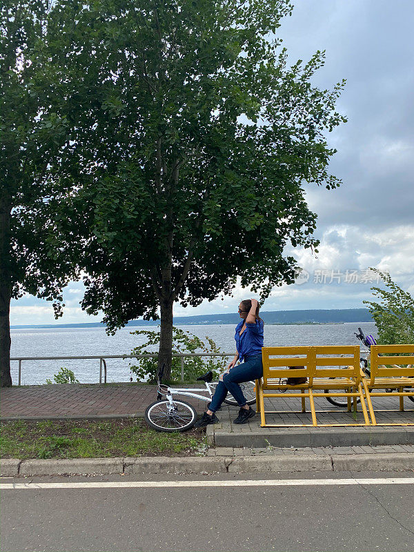 一位妇女骑着自行车，在长凳上运动后正在休息