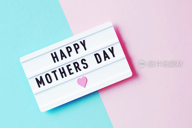 粉色和蓝色背景上的白色灯箱写着母亲节快乐