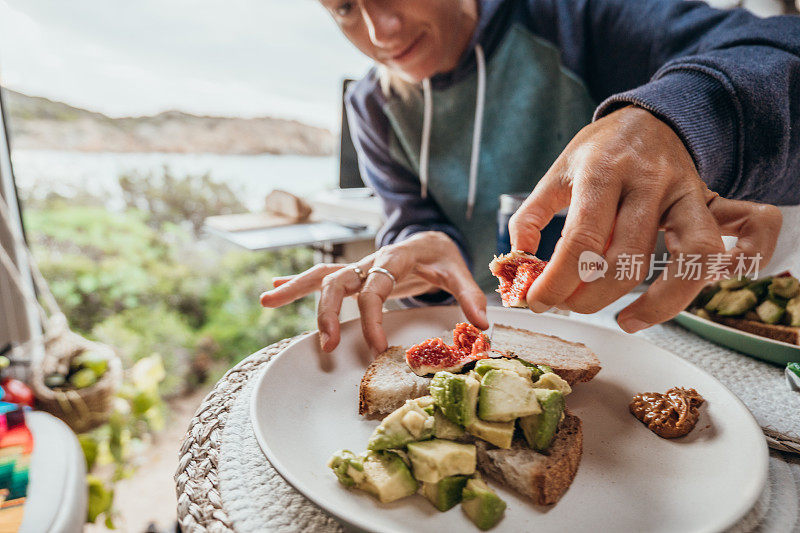 一位女士在她的货车里准备早餐，海滩景色