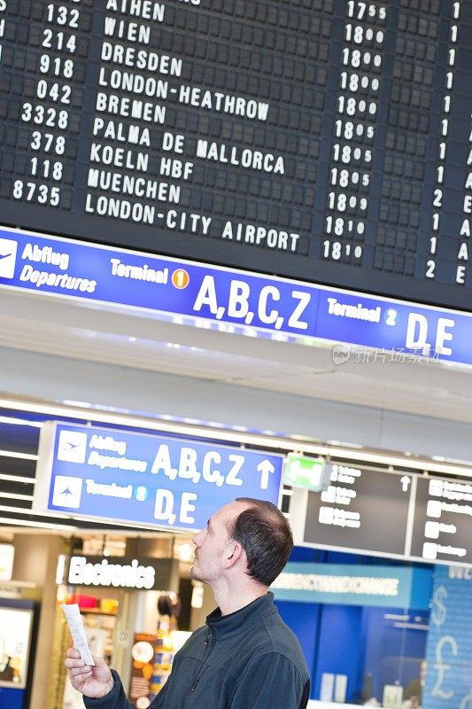 年轻的男性旅客在机场大厅查看航班信息