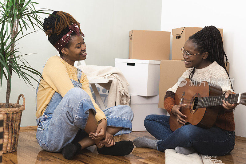 两个非洲女孩在休息，享受音乐，同时搬进来