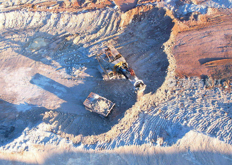 露天矿挖掘机在矿车上装载石灰石。卡车从采石场运来白垩和粘土。
