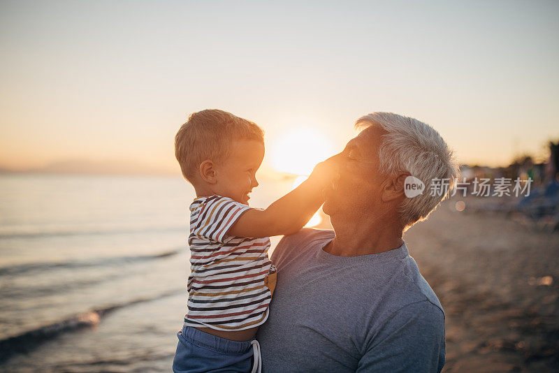 日落时分，爷爷和孙子在海滩上享受美好的一天