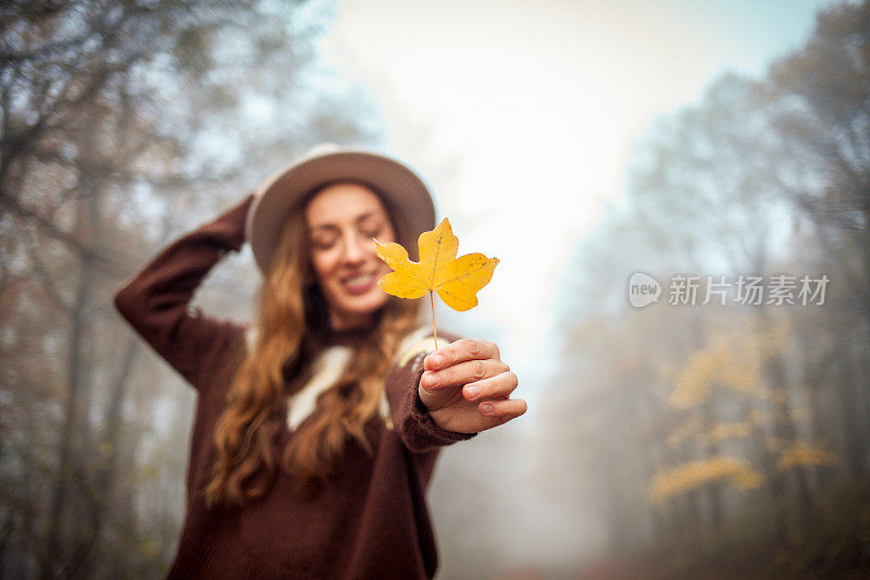 美丽的年轻女子在秋天走在户外的画像