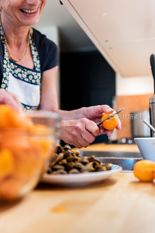 两代妇女在家里用新鲜的有机杏准备杏酱