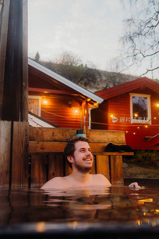 快乐的人放松在热水浴缸与风景优美的峡湾在挪威