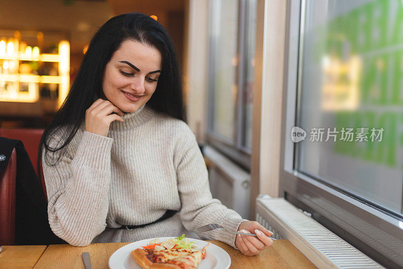 年轻漂亮的女人在餐厅吃披萨