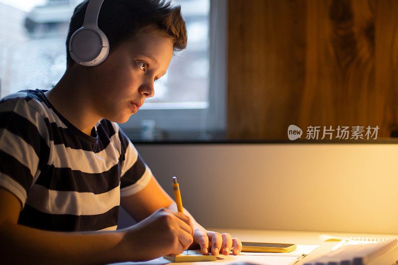 一个十几岁的男孩正在参加一个在线课程并做笔记。