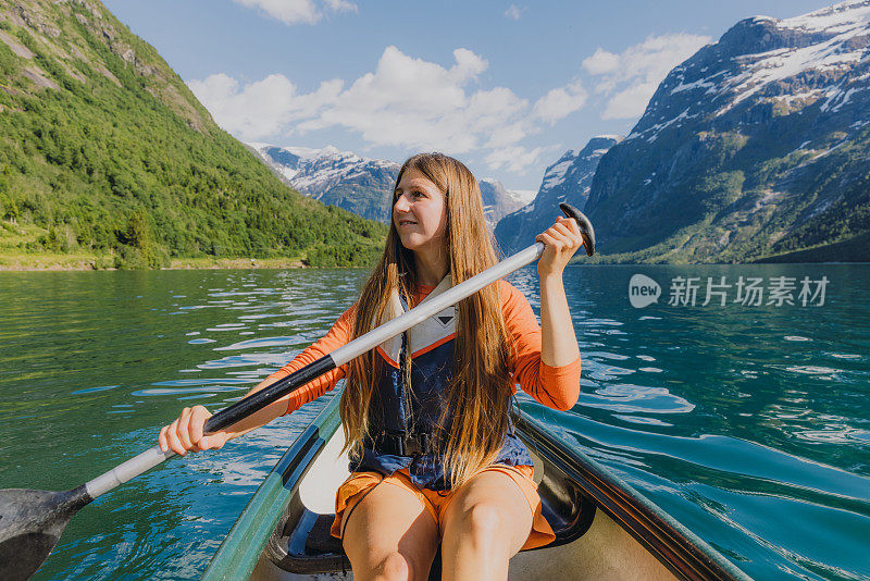 在挪威风景优美的Lovatnet湖上，微笑的女子在橙色独木舟的正面视图