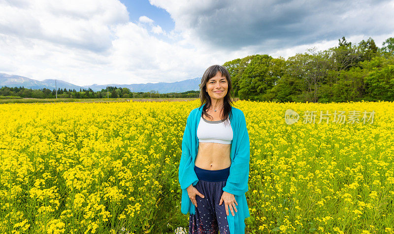 一位妇女在一片黄色的油菜花地里放松和享受户外活动