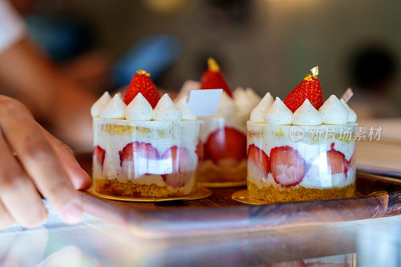 特写镜头展示了咖啡馆里木质托盘上的草莓奶油蛋糕。