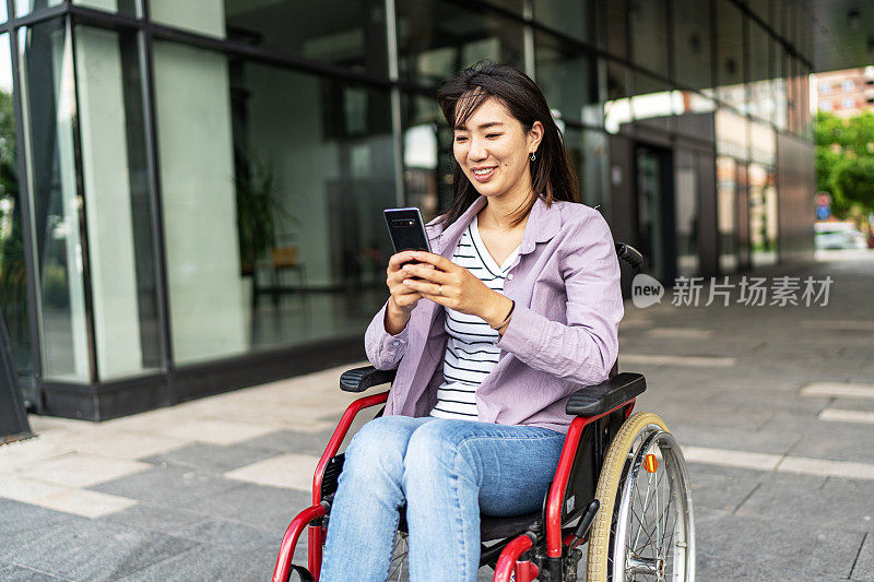 年轻美丽的亚洲女人坐在轮椅上在户外使用电话