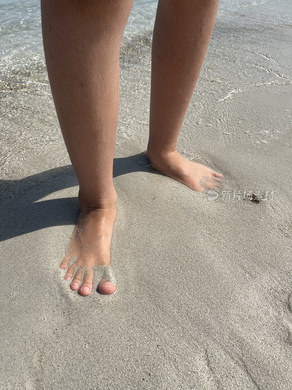 孩子的脚踩在沙滩上