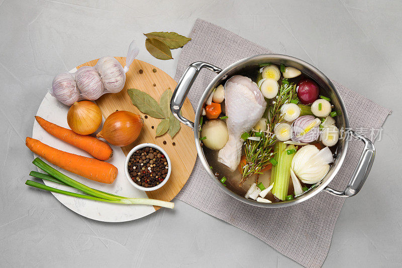 锅和不同的食材烹饪美味的清汤在浅灰色的桌子上，平铺