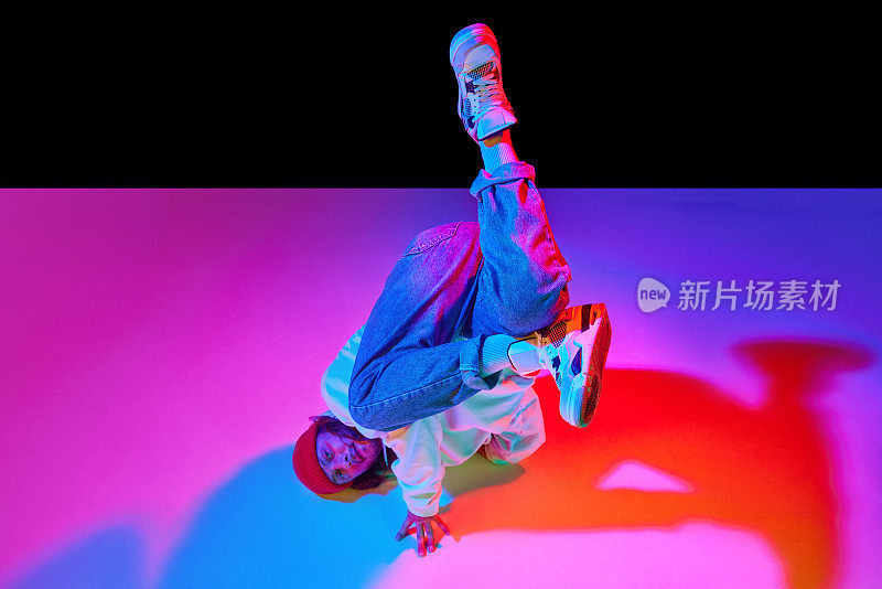 一个30多岁的动感男子，在霓虹灯的黑色工作室背景上跳着霹雳舞