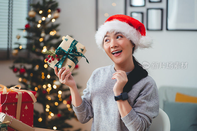 亚洲女子兴奋地摇着圣诞礼盒好奇地说。