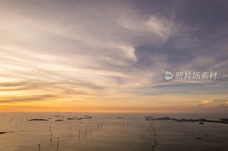 清晨，海上风力涡轮机在红色的晨光中熠熠生辉