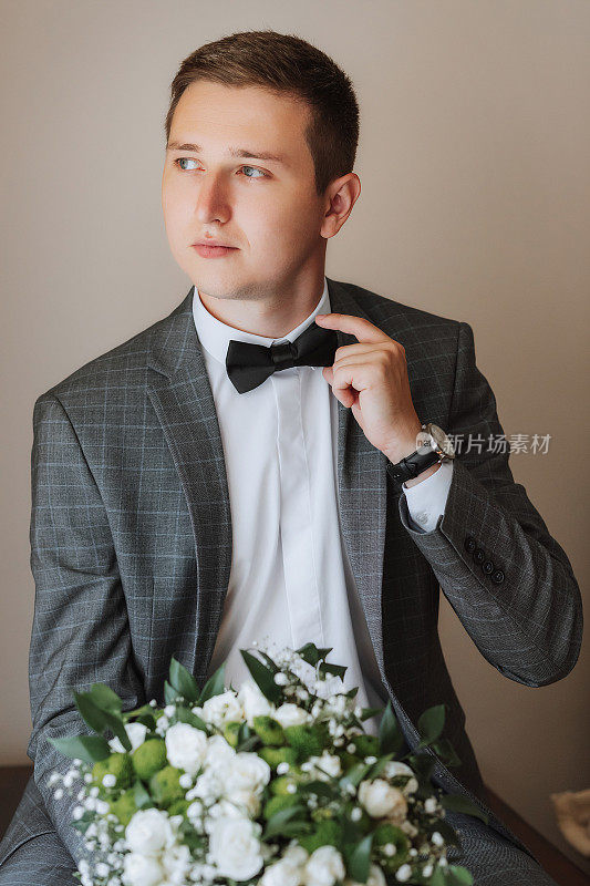 一个英俊的年轻人在婚礼前摆出新郎的姿势。新郎正在一幢大楼里为婚礼做准备
