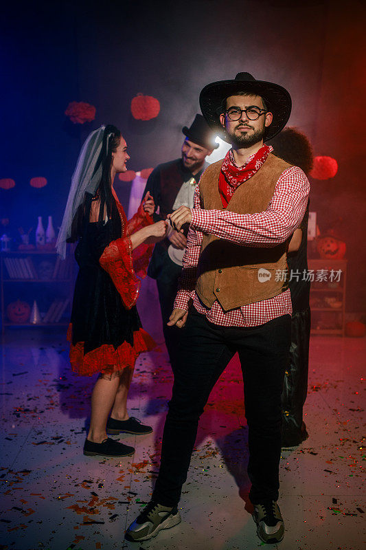 一个穿着牛仔服装的快乐年轻人在万圣节派对上跳舞