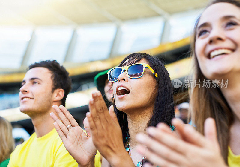 快乐的体育迷在体育场观看比赛时鼓掌欢呼