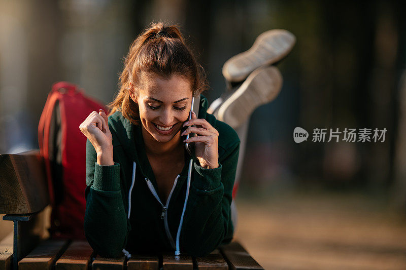 漂亮的年轻运动女性与智能手机在户外