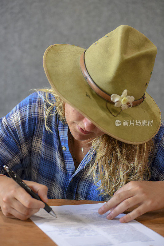 迷人的澳大利亚年轻女子在帽子填写表格。