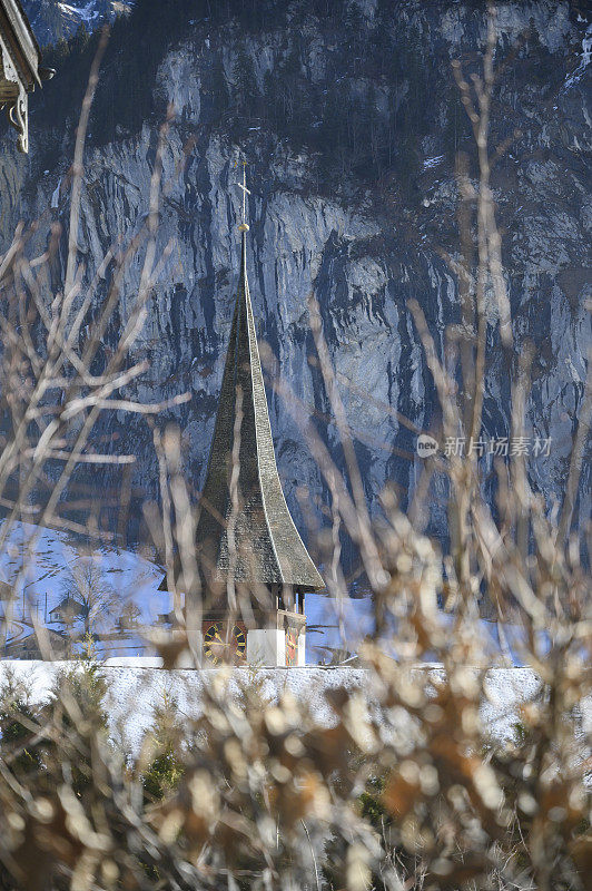 教堂的钟楼前面有山，后面有树