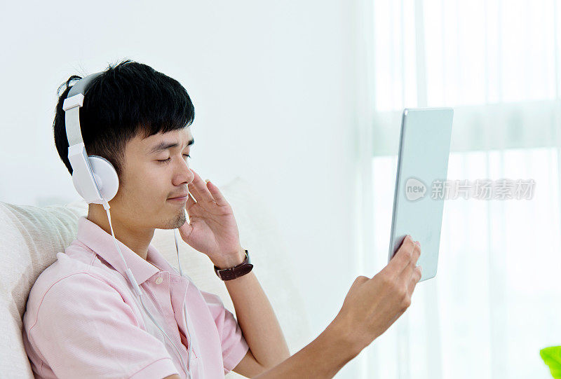 年轻的亚洲人戴着耳机欣赏音乐