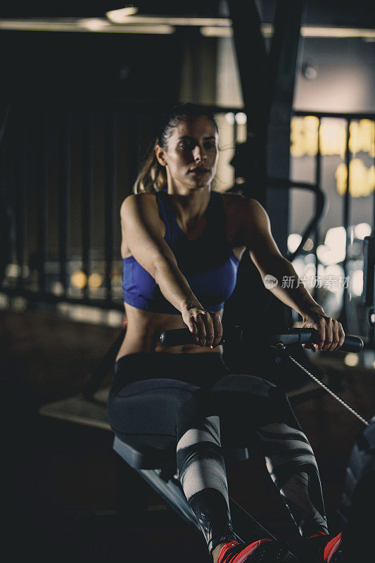健身的女人在健身房做划船机锻炼
