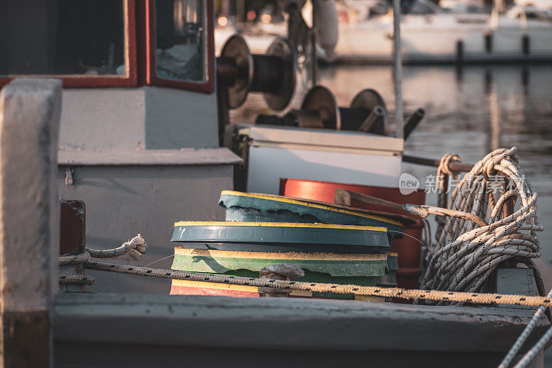 一艘近海小木船甲板上的彩色塑料桶和其他渔具
