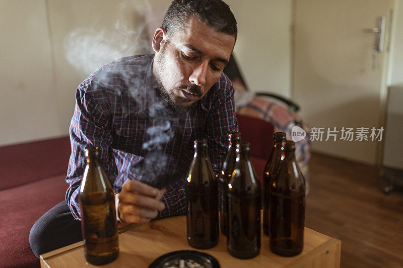 年轻悲伤的醉酒男子喝啤酒和酒精感到浪费，孤独和绝望的痛苦和情绪压力。人与酗酒、上瘾和男人抑郁的概念。