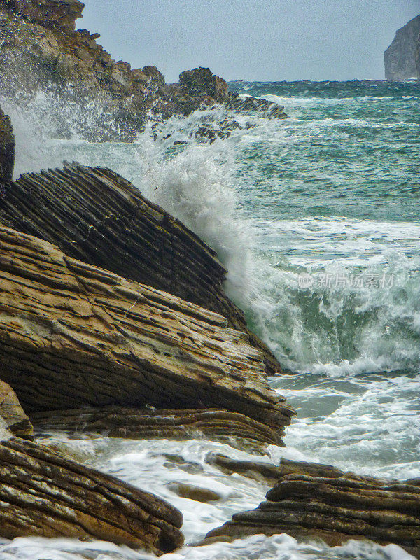 岩石嶙峋的海岸线，海浪轻轻拍打着岩石