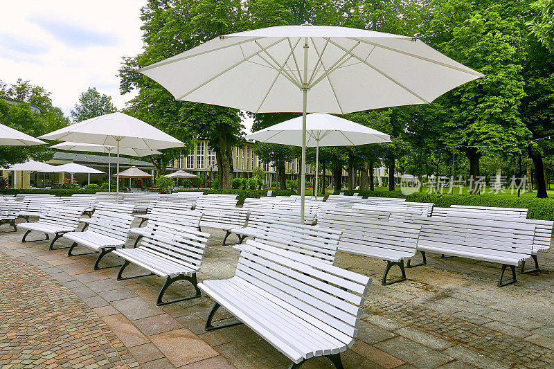 公园里有白色的长椅和雨伞