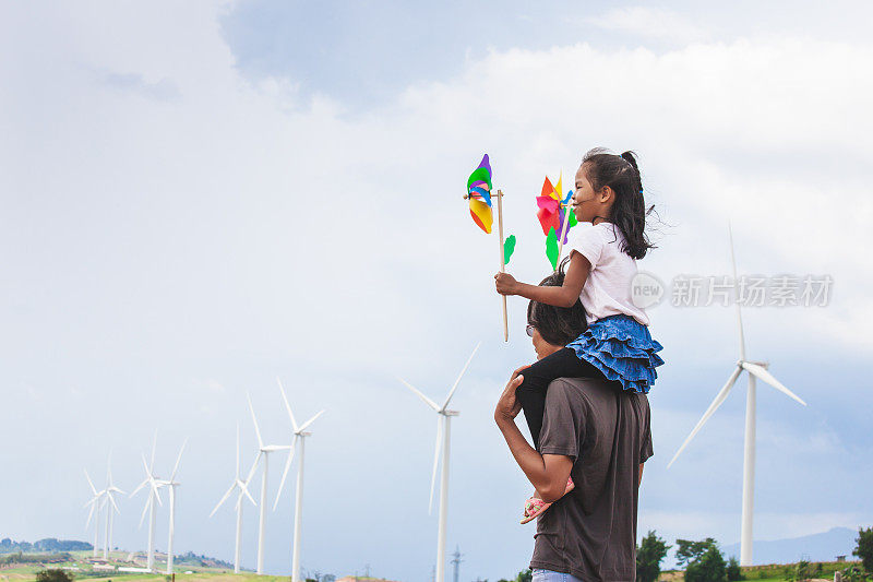 亚洲儿童女孩玩风力涡轮机和骑在父亲的肩膀在风力涡轮机领域