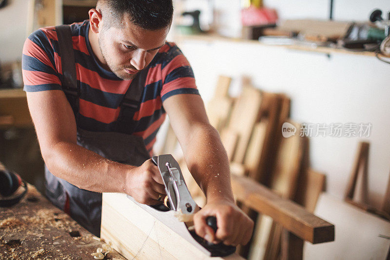 年轻的木匠正在打磨木桌