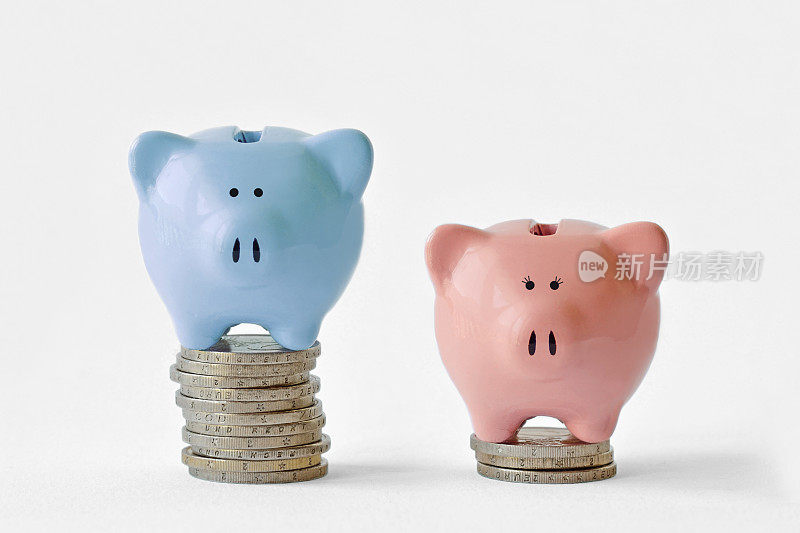 一堆硬币上的蓝色和粉色储蓄罐——性别收入差距概念