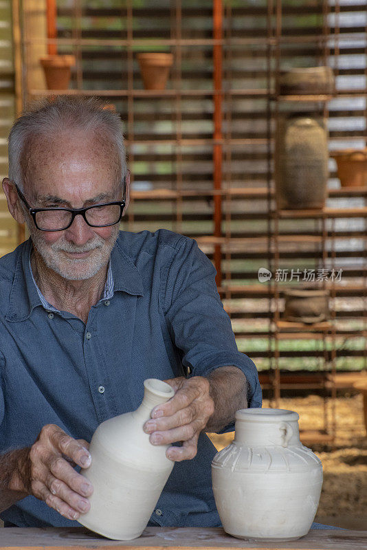 年长的男子骄傲地检查和展示他刚刚制作的陶器容器。