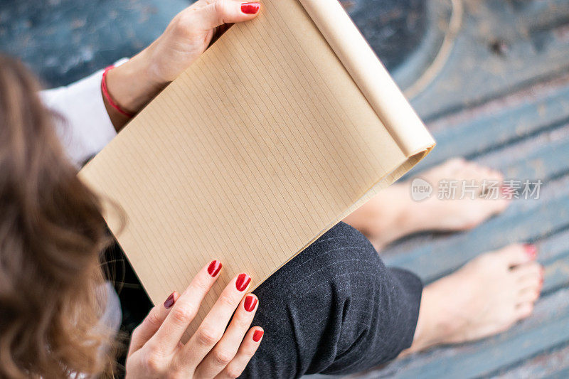 一个年轻女子赤脚坐在地板上看笔记本。