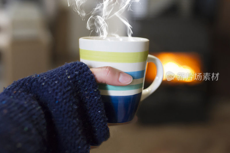 在壁炉前端着一杯茶的女人